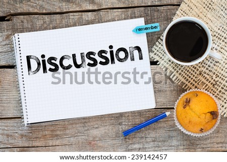 Notebook with discussion sign and sticker remember on wooden desk with cup of coffee and muffin