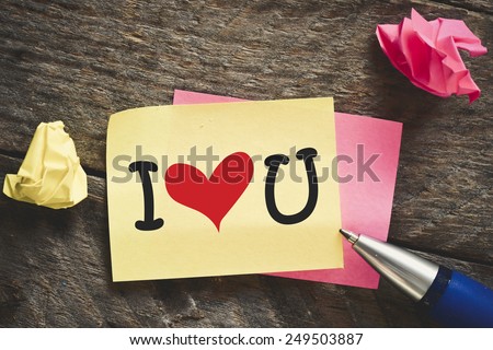 Note with I love you. Note with I love you and red heart on the wooden background with pen