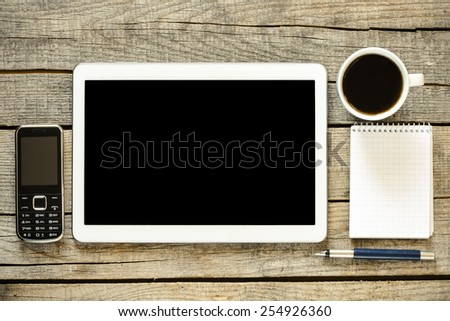 Empty tablet pc and coffee. Empty tablet pc,phone, notebook, pen and a coffee on wood table