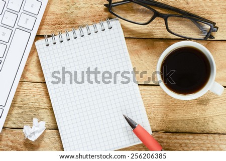Workplace with notebook and coffee. Workplace with keyboard , coffee, notebook with pen on wood table