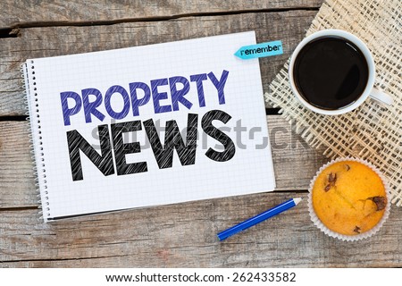 Notebook with property news and sticker remember on wooden desk with cup of coffee and muffin