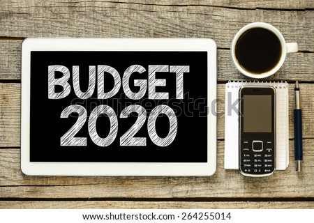 Budget 2020 on tablet pc. Budget 2020 on tablet pc with cup of coffee, notebook,mobile phone and pen on wooden background