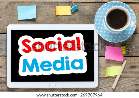 Social media on Tablet computer. Tablet computer with stickers,cup of coffee and social media on the wooden table