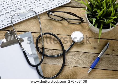 Stethoscope with clipboard and keyboard. Stethoscope,clipboard ,keyboard and green plant on wooden background