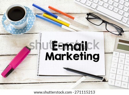 E-mail marketing and cup of coffee. E-mail marketing Written on white paper with cup of coffee ,keyboard , calculator,glasses, felt pens on wooden background
