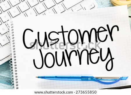 Notepad with customer journey and keyboard on wooden background