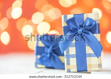 Presents with blue ribbons. Small presents with blue ribbons on red sparkle blurred background.