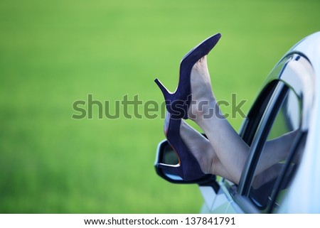 Woman legs out the windows in car with green paddy field background.The concept of relaxation and travel.