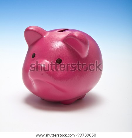Pink piggy bank or money box on a graduated blue studio background.