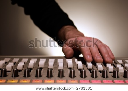 Hand adjusting sliders on a mixing board