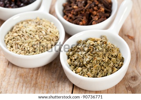 Chive and assorted dry herbs and spices in white bowls over a wooden table