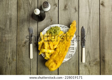 Traditional British takeaway meal of fish and chips with mushy peas on a newsprint plate