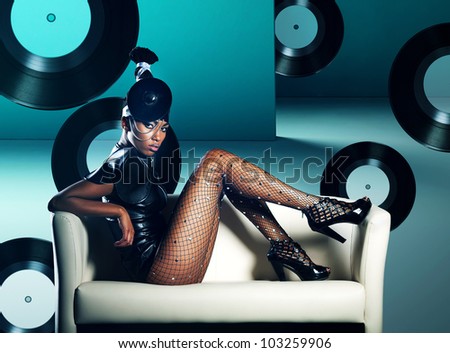 Attractive african woman siting in white chair on vinyl records background