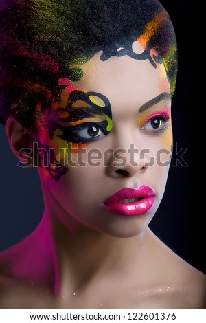 Pretty african girl with neon make up and pink light on dark blue background