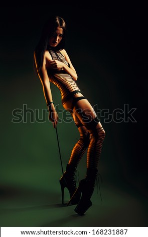 bdsm woman with whip in yellow light