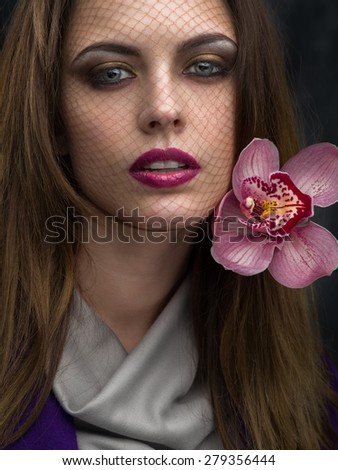 Portrait of a woman with a grid on the face and orchid in her hair close-up