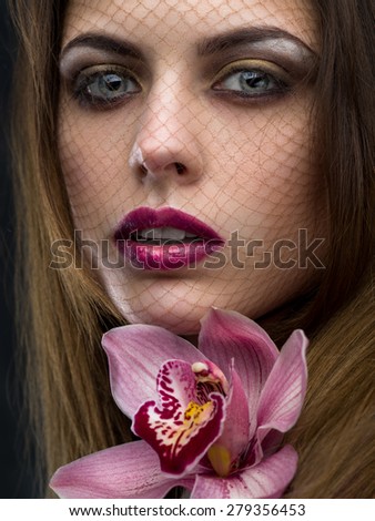 Face of woman with orchid in her hair close-up