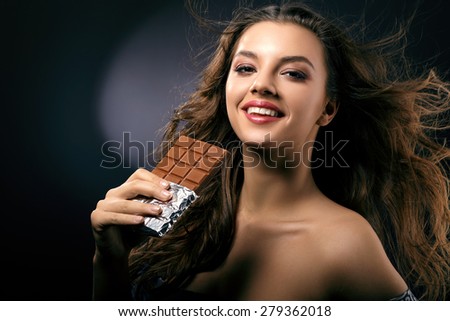Woman with flowing hair and a chocolate bar in her hand close-up