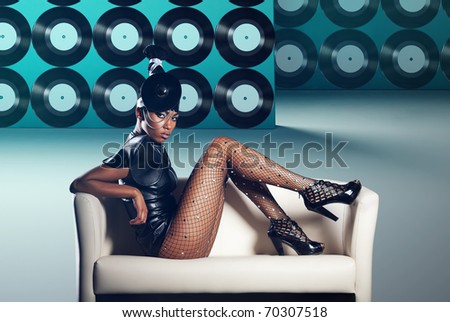 Attractive woman siting in white chair on vinyl records background