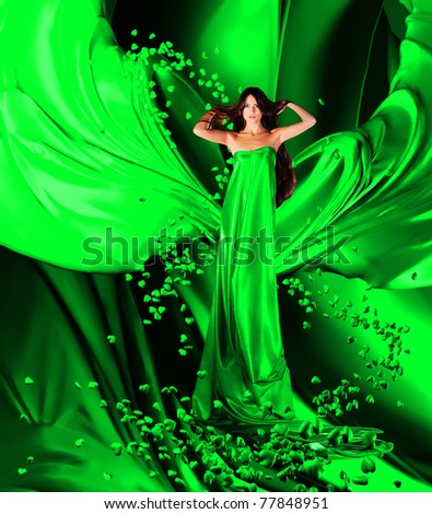 goddess of love in long green dress with magnificent long hair makes a magic ritual of connecting hearts of people on green drapery, fabric