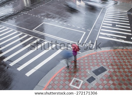 People waiting zebra crossing  on big city street in the rain.