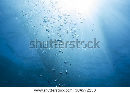 Abstract underwater scene sun ray and air bubbles in deep blue sea.