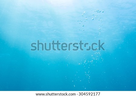 Abstract underwater scene sun ray and air bubbles in deep blue sea.