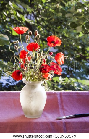 Poppies in the vase, at the window with paintbrush