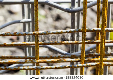 Metallic lattice with rust over another metallic lattices with soil texture in the background