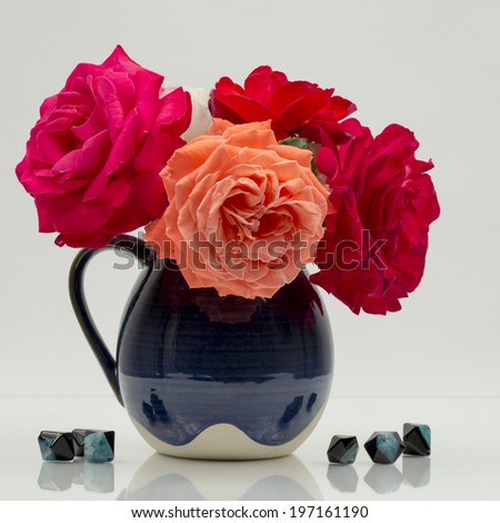 still life composition with colorful, beautiful, delicate roses in a ceramic vase with agate stones near