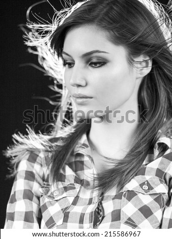 Beautiful caucasian long haired girl posing with dark background and contour light. Photo has grain texture visible on its maximum size. Artistic black and white photography