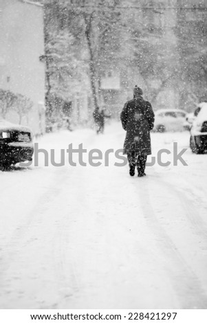 Snowing urban landscape with people passing by