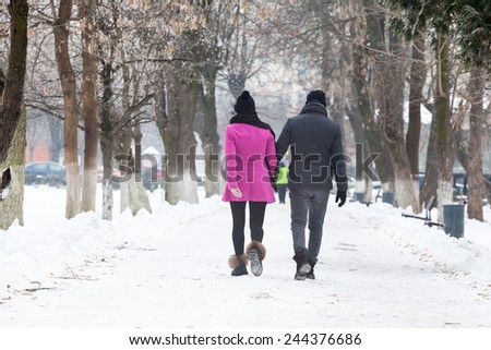 Urban landscape with couple walking in the snow
