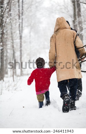 Snowing landscape in the park with poor people carying wood sticks and branches