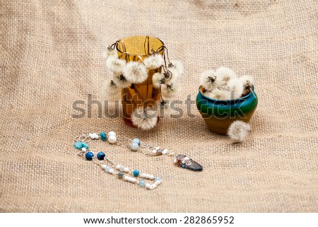 Composition with dandelion seeds, small objects and jewels with burlap texture