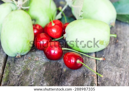 Green, summer apples and cherries with old wood texture