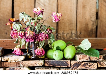 Green, summer apples and dried roses with old wood texture