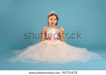 Little beautiful girl sitting in white spruce dress and crown with string of beads in hands