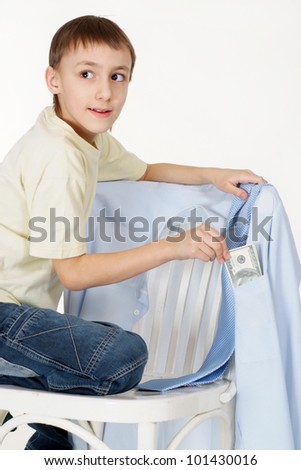 Handsome young lad gets money from the shirts hanging on a chair on a white background