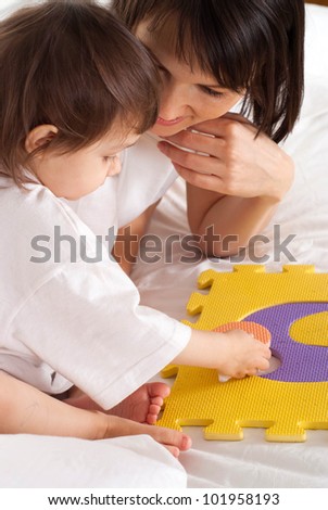 A beautiful mother with her daughter play with a mat in the bed