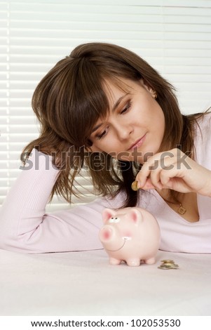 A beautiful caucasian girl sitting at a cafe with a piggy bank