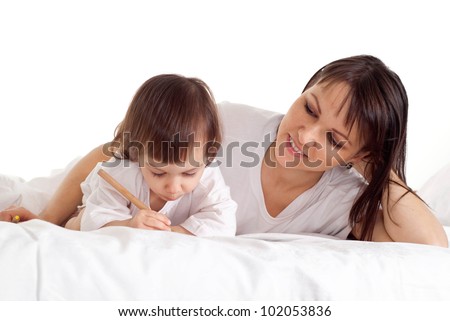 A good Caucasian mum with her daughter lying on the bed with a pencil