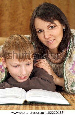 Happy nice Caucasian mom with her son reading a book on a brown background