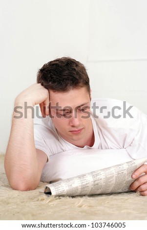Pretty Caucasian man lying on a rug on a light background