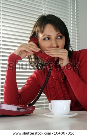 Happy Caucasian woman sitting with a phone on a light background