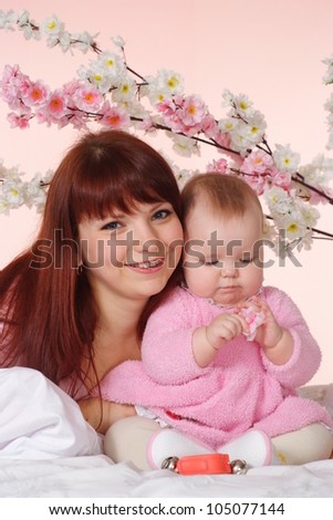 A good Caucasian mother with her daughter lying in bed on a light background