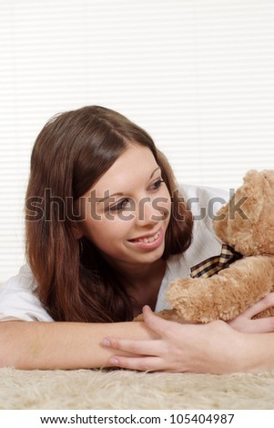 Luck Caucasian woman lying on a carpet with a toy bear