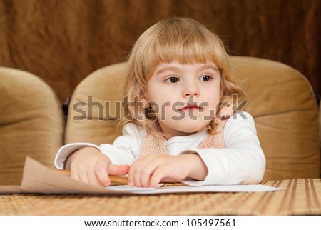Good Caucasian young baby draws a table on a brown background