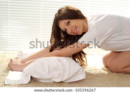 A beautiful caucasian girl stretches on the carpet against the window