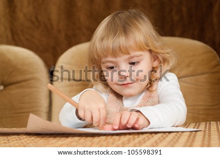 Nice Caucasian young baby draws a table on a brown background